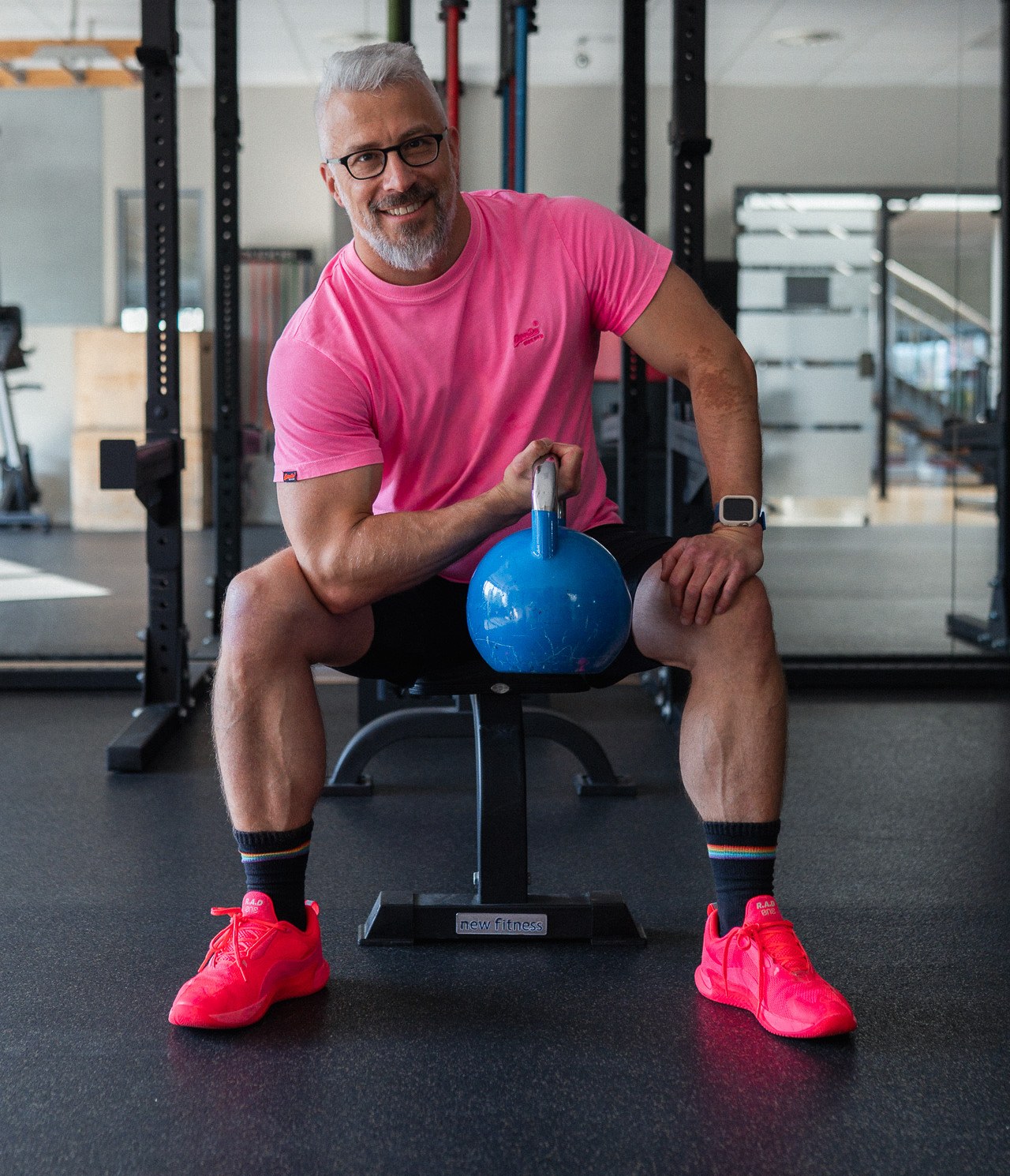 Thomas Kuballa lächelt im Fitnessstudio, sitzend mit einem Kettlebell in der Hand